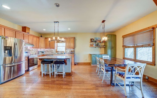 kitchen featuring pendant lighting, a kitchen island, stainless steel fridge, light hardwood / wood-style floors, and stove