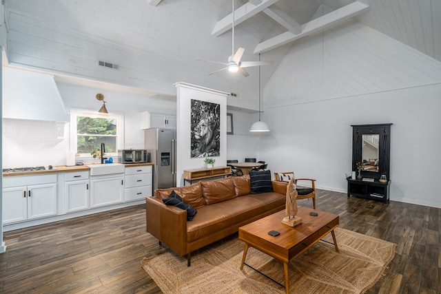 living room featuring dark wood-type flooring, high vaulted ceiling, beam ceiling, and sink