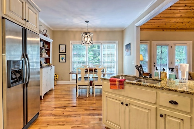 kitchen with light wood-type flooring, ornamental molding, a notable chandelier, stainless steel refrigerator with ice dispenser, and light stone counters