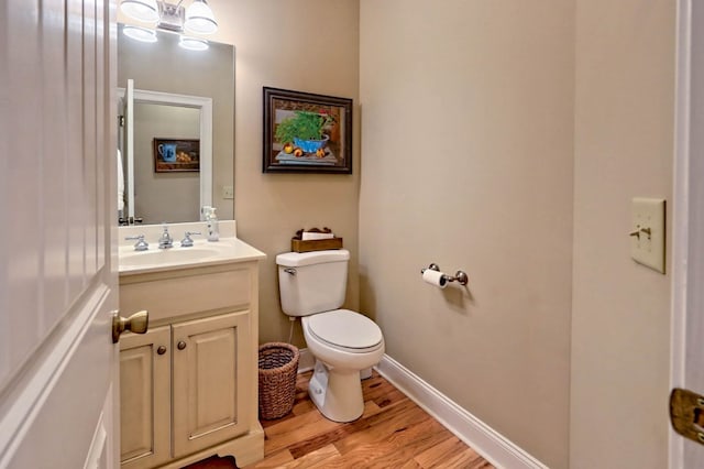 bathroom with toilet, vanity, and wood-type flooring