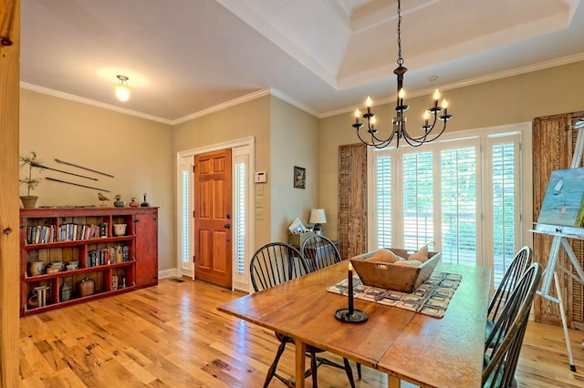 dining area with crown molding, hardwood / wood-style flooring, a chandelier, and a raised ceiling