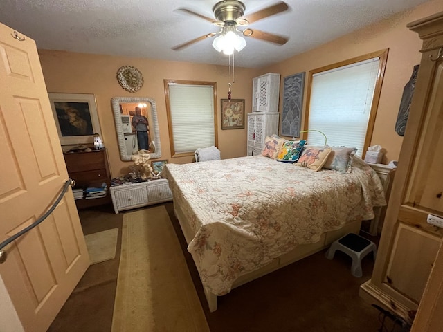 bedroom with ceiling fan, dark colored carpet, and a textured ceiling