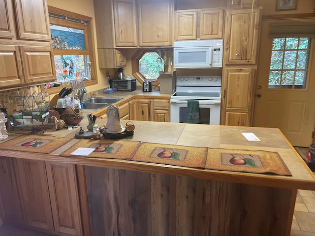 kitchen featuring kitchen peninsula, white appliances, sink, and light tile patterned flooring