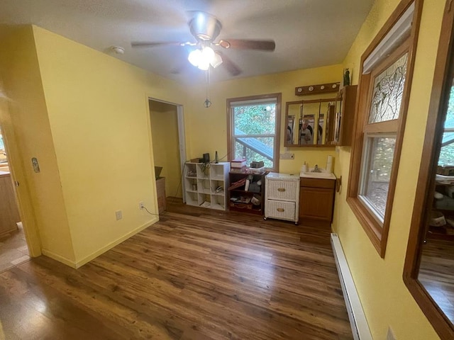 home office with ceiling fan, dark hardwood / wood-style floors, sink, and a baseboard heating unit