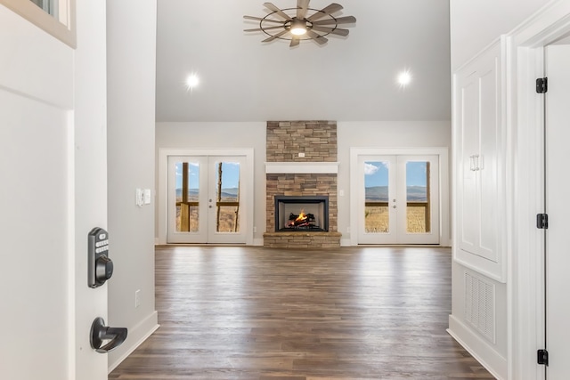 unfurnished living room featuring a stone fireplace, dark hardwood / wood-style flooring, and french doors