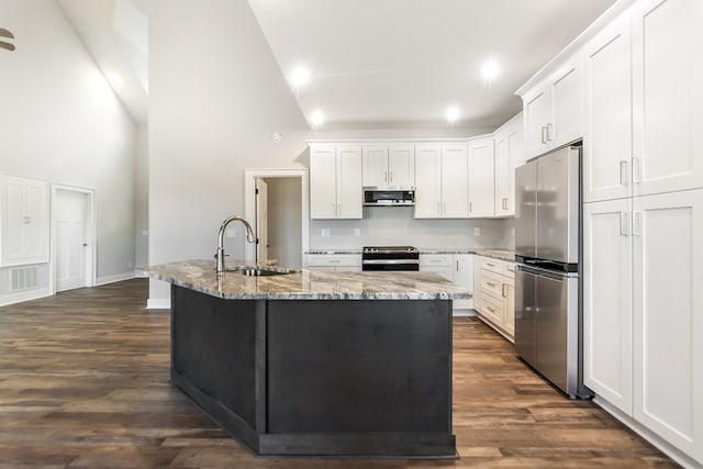 kitchen with sink, white cabinets, stainless steel appliances, light stone countertops, and a center island with sink