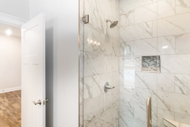 bathroom with a stall shower, wood finished floors, and baseboards