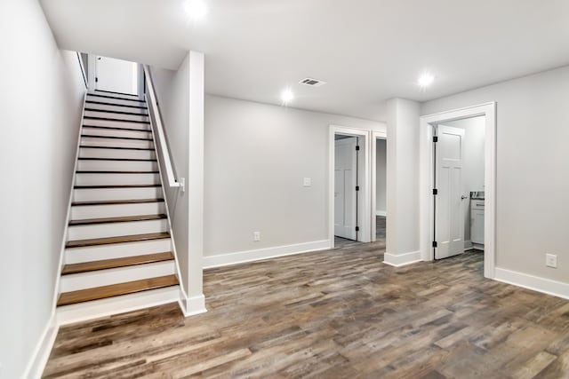 below grade area with baseboards, stairs, visible vents, and wood finished floors