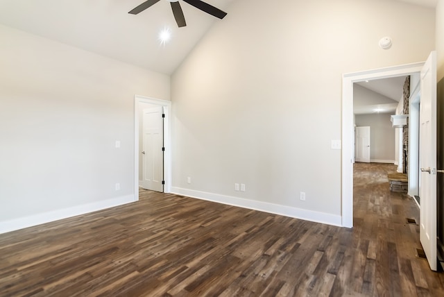 empty room with baseboards, dark wood finished floors, ceiling fan, a fireplace, and high vaulted ceiling