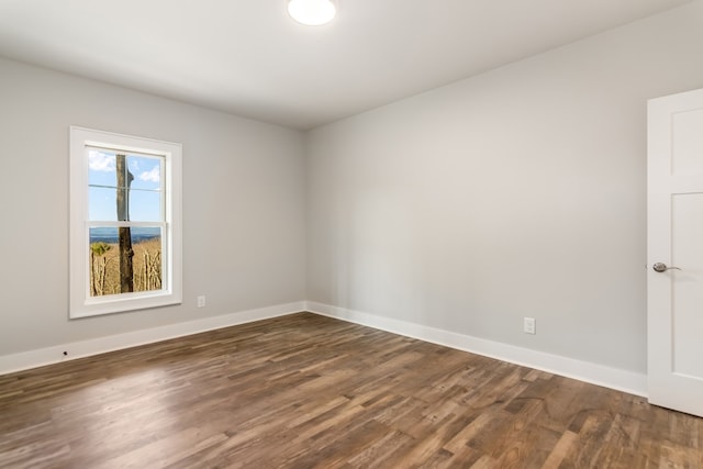 spare room with dark wood-type flooring and baseboards