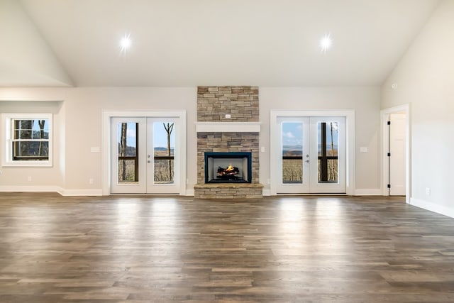 unfurnished living room with french doors, baseboards, a stone fireplace, and dark wood-style flooring