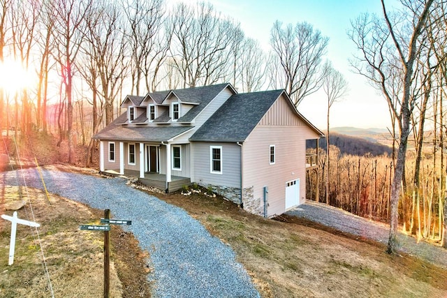 view of front of property with driveway, an attached garage, a porch, and a shingled roof