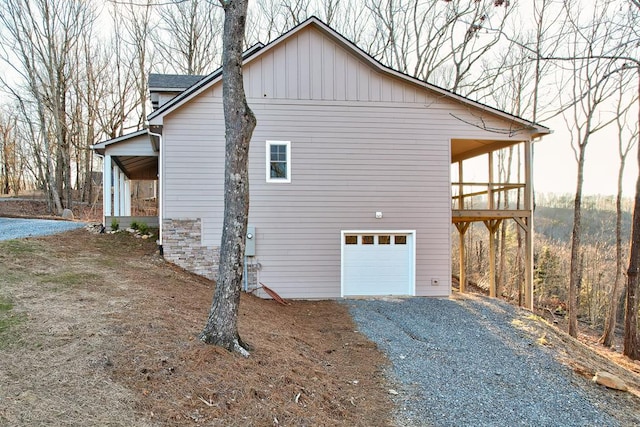 view of side of property with board and batten siding, gravel driveway, and a garage