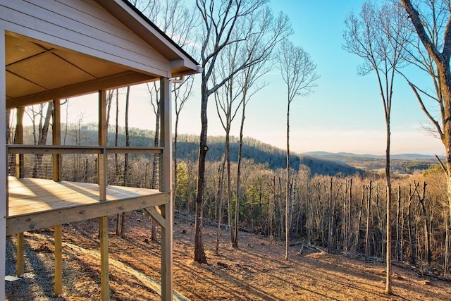 exterior space with a deck with mountain view and a view of trees