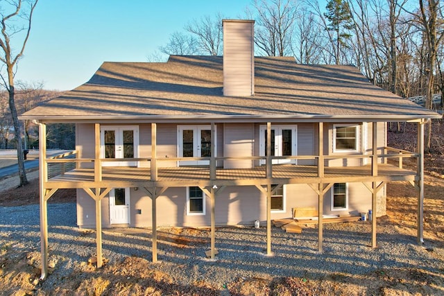 back of property featuring a chimney, a deck, and french doors