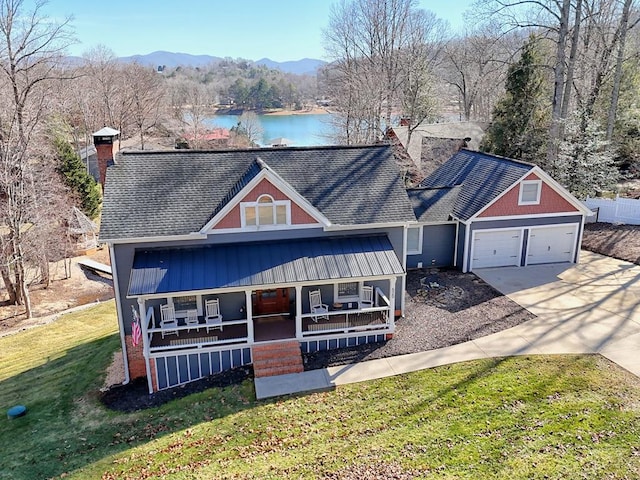 view of front facade with a porch, a garage, a front lawn, and a water and mountain view