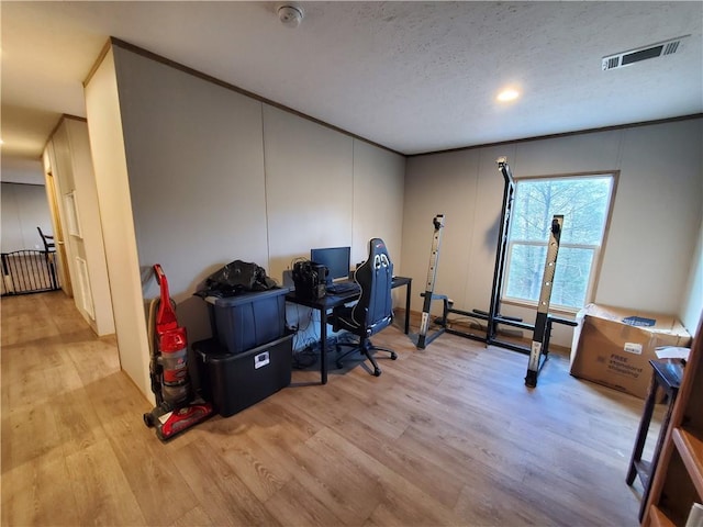 office area with a textured ceiling, light hardwood / wood-style floors, and crown molding