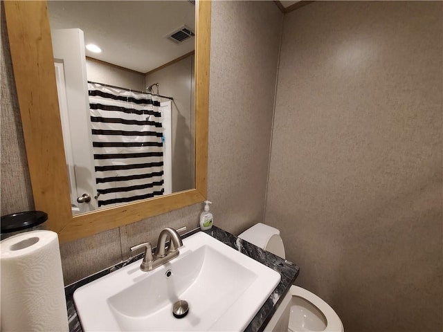 bathroom featuring curtained shower, sink, and toilet