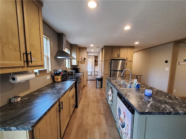 kitchen featuring sink, wall chimney range hood, an island with sink, light hardwood / wood-style floors, and appliances with stainless steel finishes