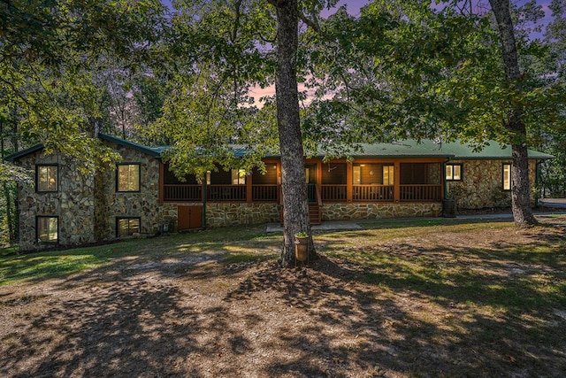 back house at dusk featuring covered porch