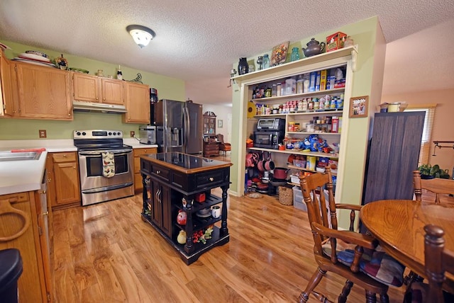 kitchen with light hardwood / wood-style flooring, a textured ceiling, stainless steel appliances, and light brown cabinetry