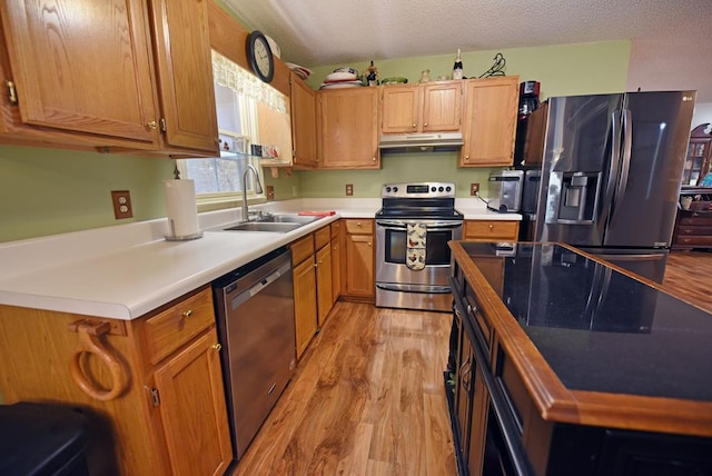 kitchen featuring light hardwood / wood-style floors, a textured ceiling, stainless steel appliances, and sink