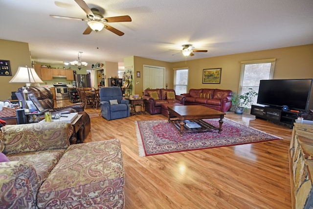 living room featuring a textured ceiling, light hardwood / wood-style flooring, and ceiling fan with notable chandelier