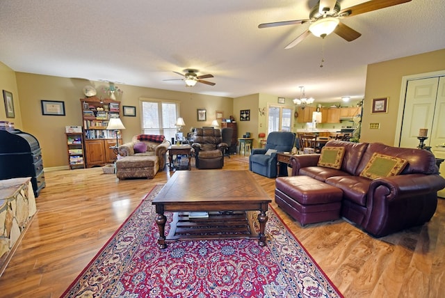 living room featuring hardwood / wood-style floors, a textured ceiling, and ceiling fan with notable chandelier