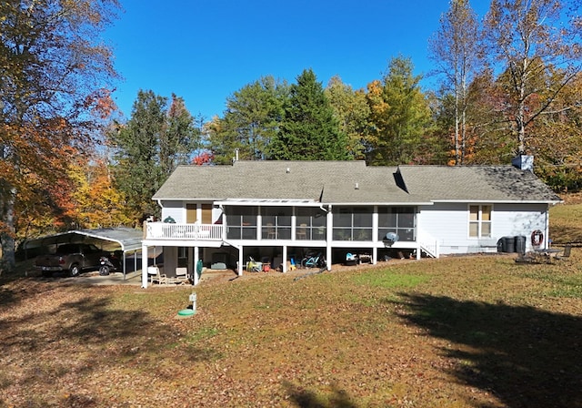 rear view of property featuring a yard, a carport, and a sunroom