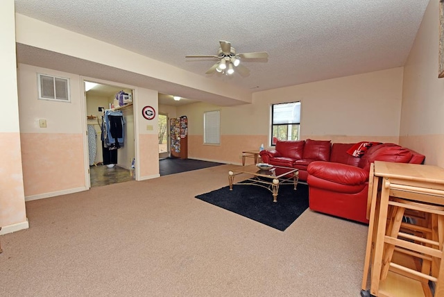 carpeted living room with ceiling fan and a textured ceiling