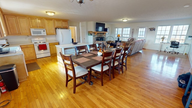 dining space with sink, light wood-type flooring, and a fireplace