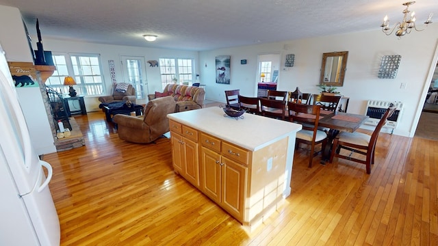 kitchen featuring a kitchen island, a notable chandelier, light hardwood / wood-style floors, a textured ceiling, and decorative light fixtures