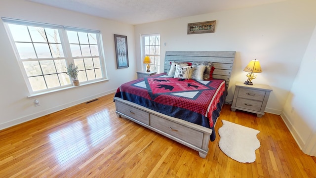 bedroom with a textured ceiling and light hardwood / wood-style flooring