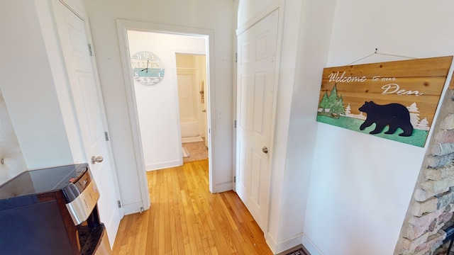 hallway with washer / dryer and light hardwood / wood-style floors