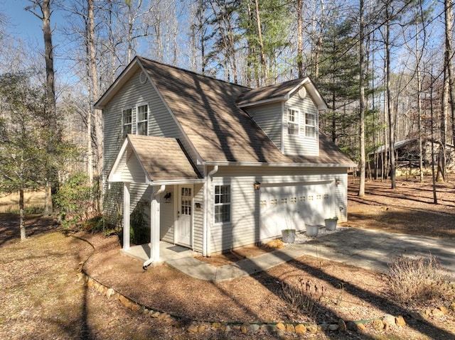 view of front of home featuring a garage, driveway, and a shingled roof