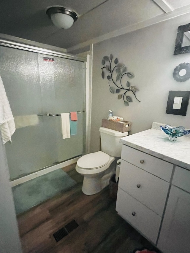 bathroom featuring vanity, toilet, hardwood / wood-style flooring, and walk in shower