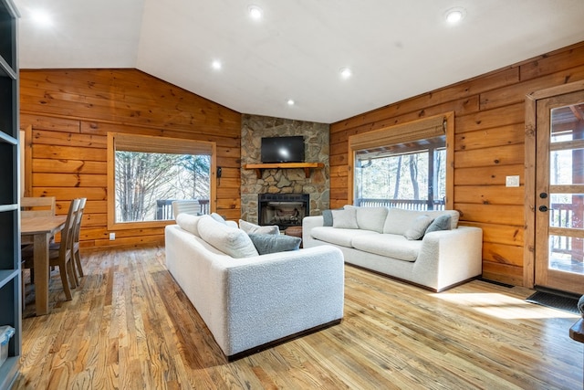 living room featuring wood walls, light hardwood / wood-style floors, and lofted ceiling