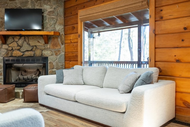 living room with a fireplace, light hardwood / wood-style floors, and wood walls