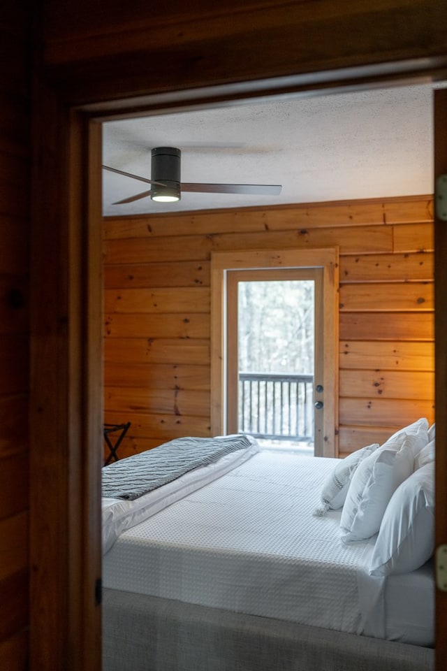 bedroom with access to outside, wooden walls, and ceiling fan