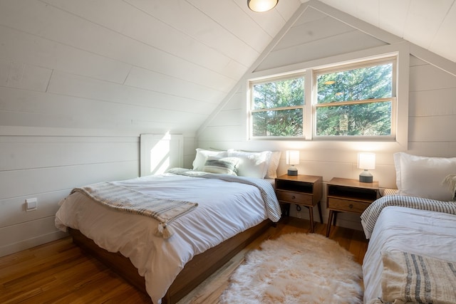 bedroom with wood walls, wood-type flooring, and vaulted ceiling