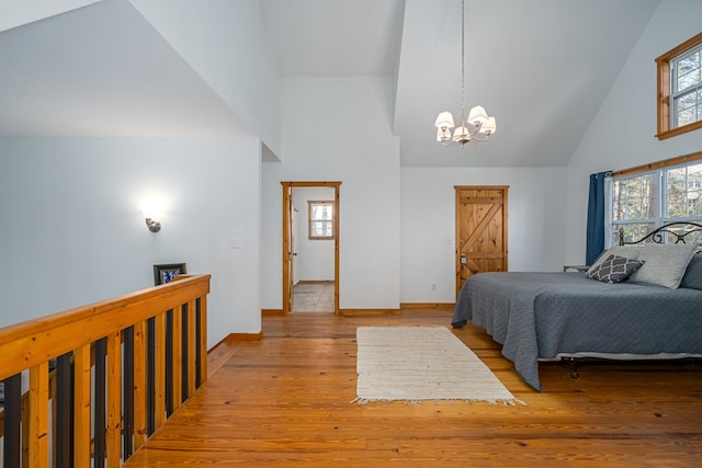 bedroom with high vaulted ceiling, light hardwood / wood-style floors, and a chandelier