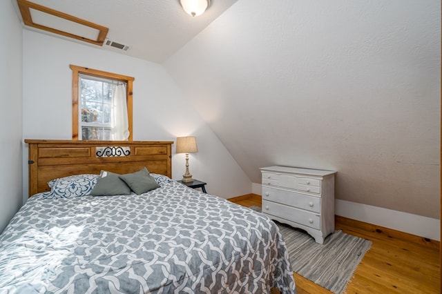 bedroom with vaulted ceiling and light hardwood / wood-style flooring