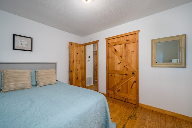 bedroom featuring hardwood / wood-style flooring and a textured ceiling