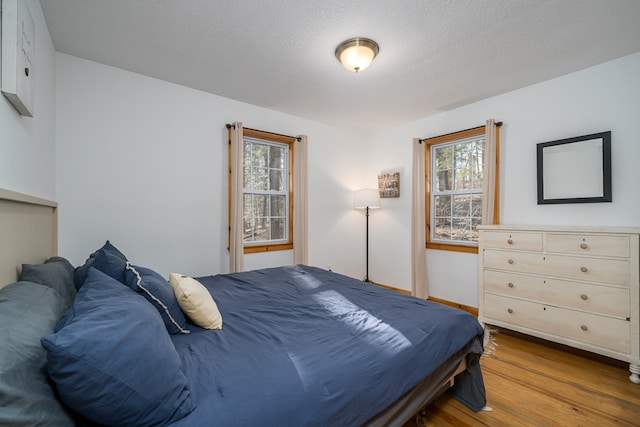 bedroom with a textured ceiling and light wood-type flooring