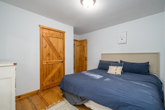 bedroom with a textured ceiling and light hardwood / wood-style floors