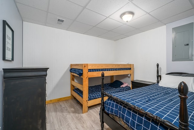 bedroom featuring hardwood / wood-style floors, electric panel, and a drop ceiling