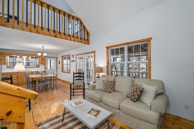 living room featuring an inviting chandelier, hardwood / wood-style floors, high vaulted ceiling, and french doors