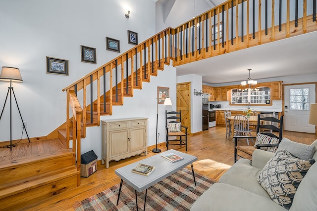 living room featuring a high ceiling, sink, an inviting chandelier, and light hardwood / wood-style floors