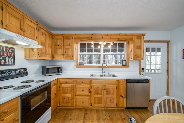 kitchen featuring stainless steel appliances, sink, a textured ceiling, and light wood-type flooring