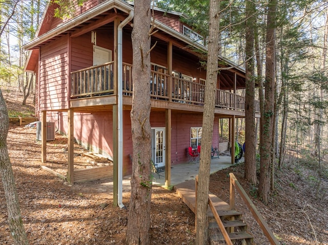 rear view of house featuring a wooden deck, central AC, and a patio area